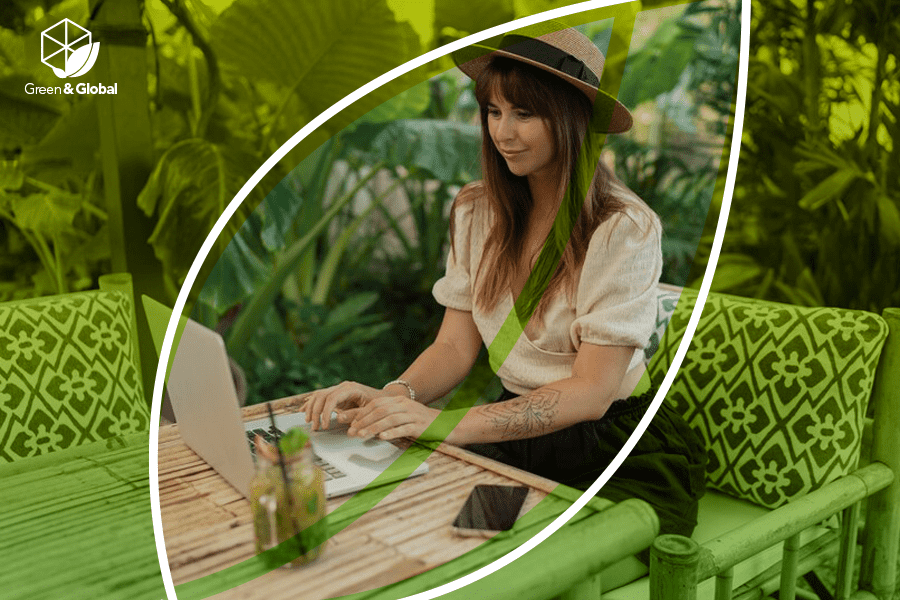 This illustration shows a woman using her laptop with plants in the background and the vFairs Green & Global campaign logo.